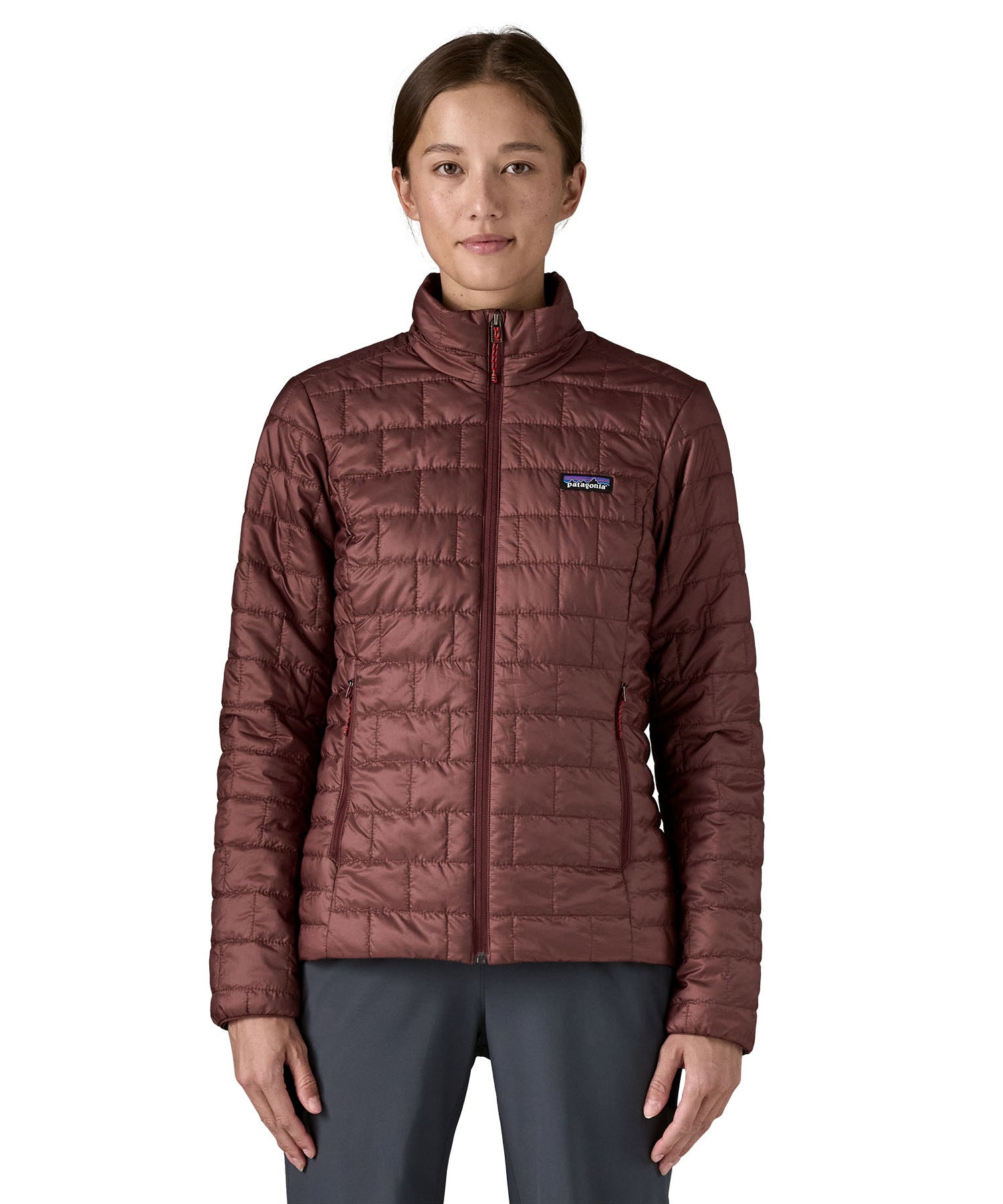 A female model wearing the Patagonia women's nano puff jacket in dark ruby showing the front fit of the jacket with a closed zip