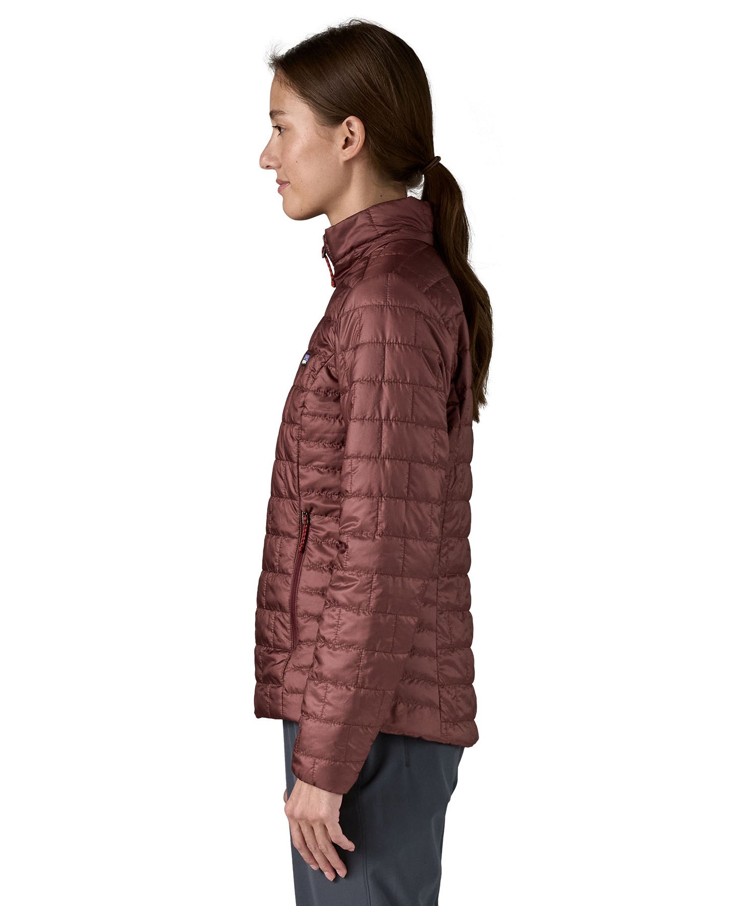 The side of the Patagonia women's nano puff jacket in dark ruby. Jacket is worn by a female model and showing the arm fit of the jacket