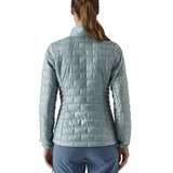A female model wearing the Patagonia women's nano puff jacket in thermal blue showing the back fit of the jacket