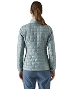 A female model wearing the Patagonia women's nano puff jacket in thermal blue showing the back fit of the jacket