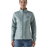 A female model wearing the Patagonia women's nano puff jacket in thermal blue showing the front fit of the jacket with a closed zip