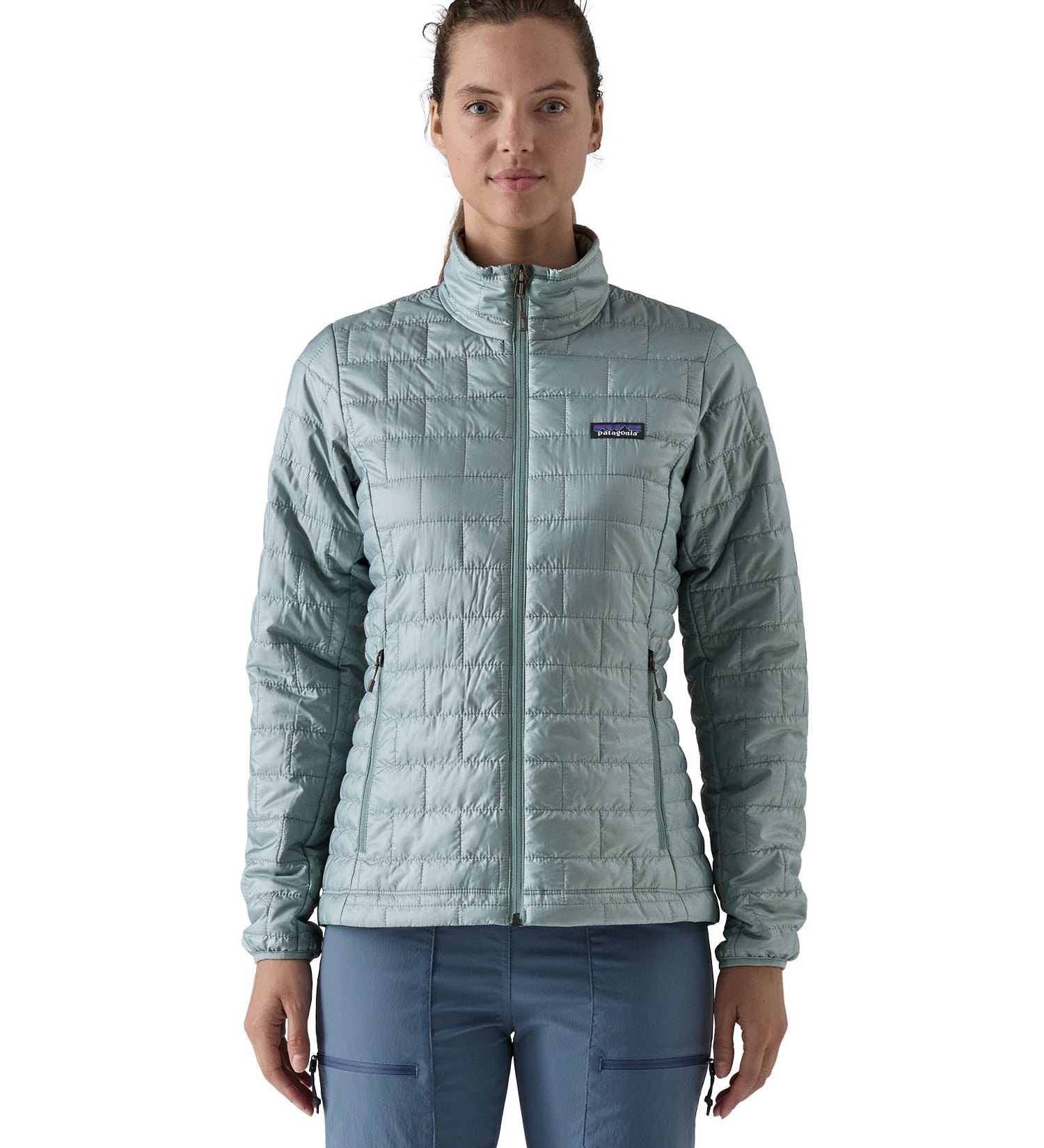 A female model wearing the Patagonia women's nano puff jacket in thermal blue showing the front fit of the jacket with a closed zip