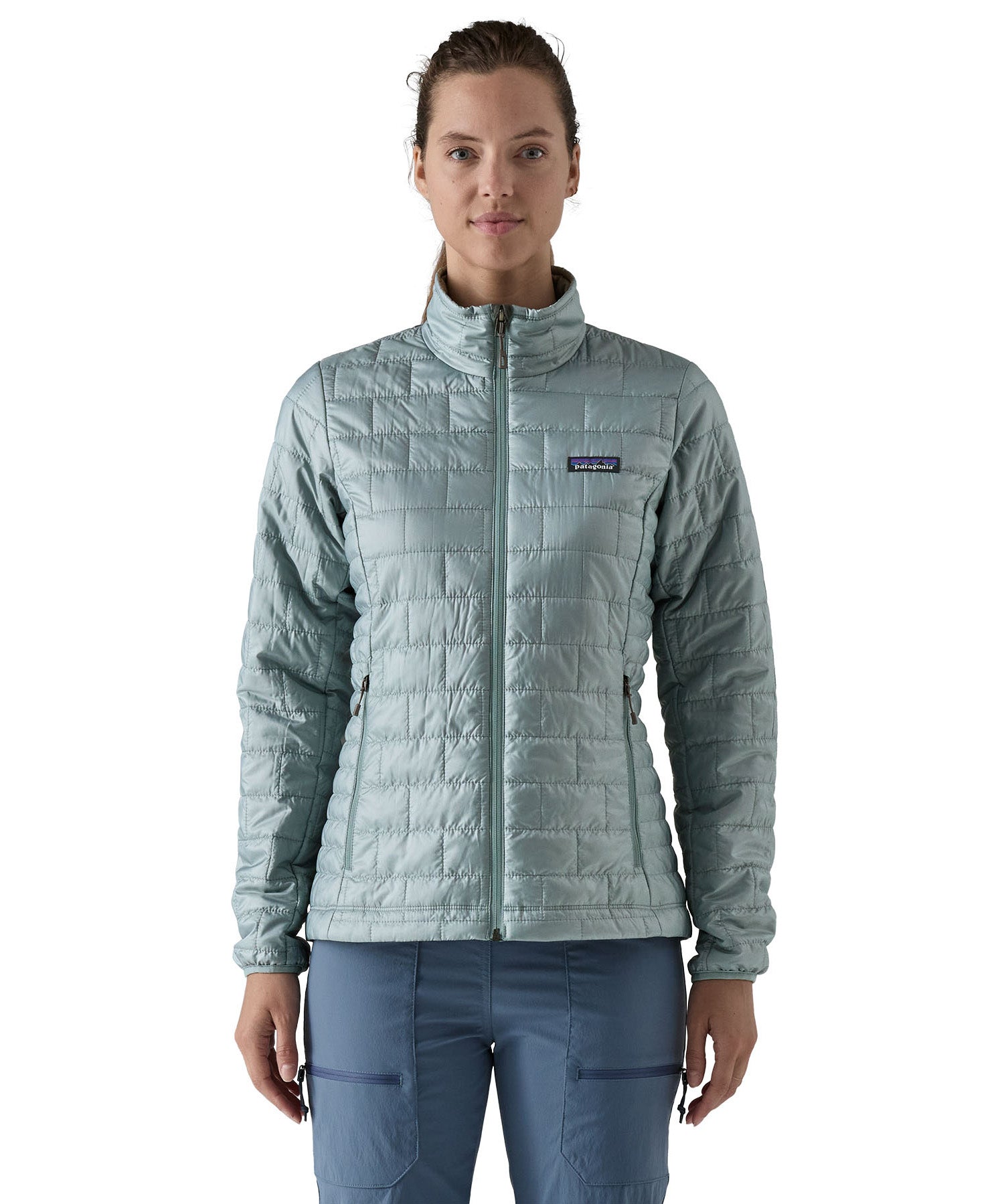 A female model wearing the Patagonia women's nano puff jacket in thermal blue showing the front fit of the jacket with a closed zip