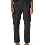 Close up of a female standing in front of a white background wearing sandals and the Patagonia women's lightweight cargo trousers in black showing the belt and side pockets