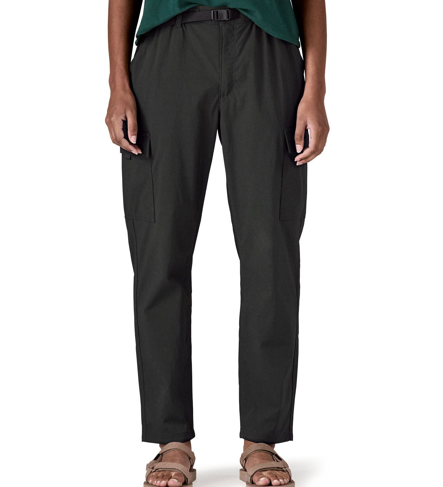 Close up of a female standing in front of a white background wearing sandals and the Patagonia women's lightweight cargo trousers in black showing the belt and side pockets