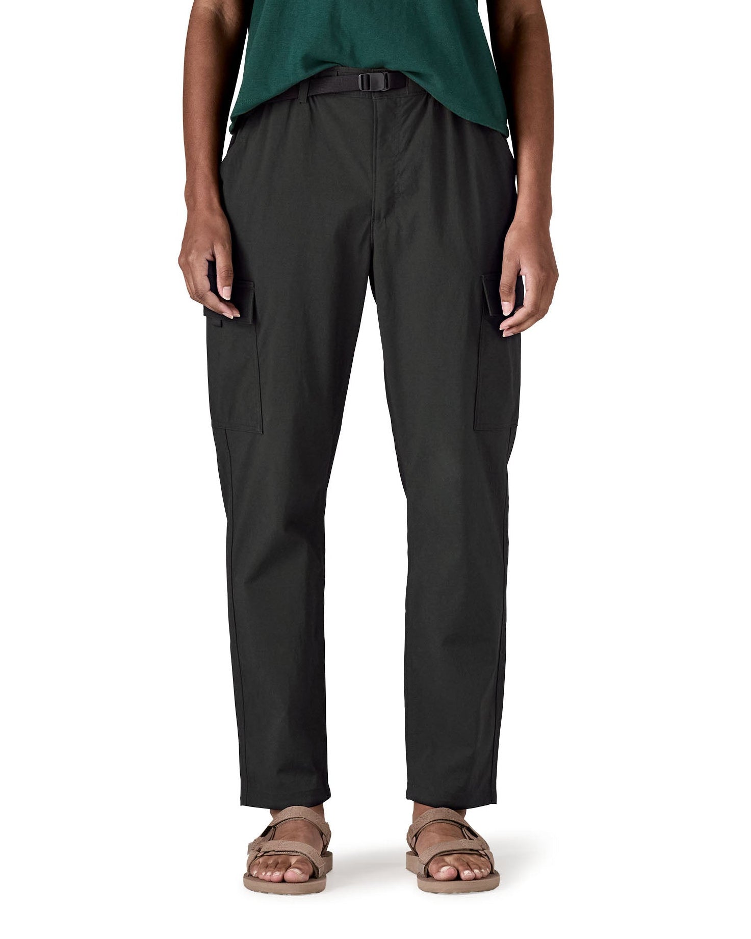 Close up of a female standing in front of a white background wearing sandals and the Patagonia women's lightweight cargo trousers in black showing the belt and side pockets