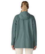 Back of woman wearing Patagonia outdoor everyday rain jacket in blue with the hood down.