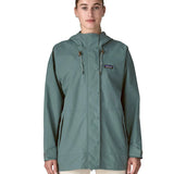 Woman wearing Patagonia outdoor everyday rain jacket in blue sage full zipped showing hood toggles. Coat has a relaxed fit