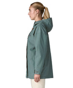 Side of woman wearing Patagonia outdoor everyday rain jacket in blue sage. Coat has a straight hemline falls below the bum
