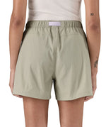 Back of woman wearing Patagonia's women's outdoor everyday shorts in light grey with light purple belt. 