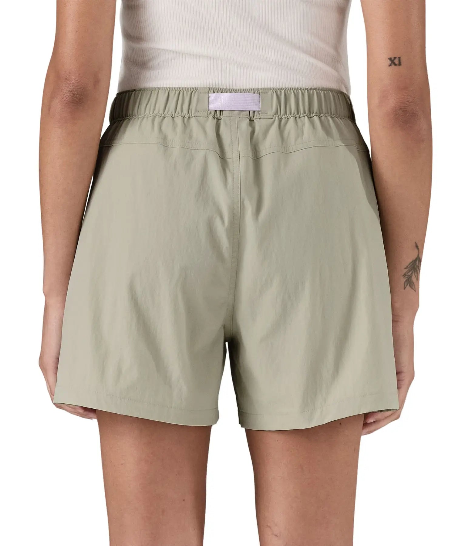 Back of woman wearing Patagonia's women's outdoor everyday shorts in light grey with light purple belt. 