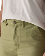 A close up of the female wearing a white and the Patagonia women's canvas trousers in light green colour showing the button fastener detail