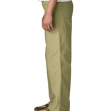 The side of the female standing in front of a white background wearing a white t-shirt brown trainers and the Patagonia women's canvas trousers with a wide leg in light green colour showing the leg length