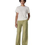Female standing in front of a white background wearing a white t-shirt brown trainers and the Patagonia women's canvas trousers with a wide leg in light green colour
