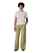 Female standing in front of a white background wearing a white t-shirt brown trainers and the Patagonia women's canvas trousers with a wide leg in light green colour