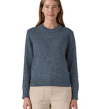 A woman wearing the Patagonia Women's Recycled Wool-Blend Crewneck Sweater. A thick knit jumper in dark blue with dappled design available at Babipur.