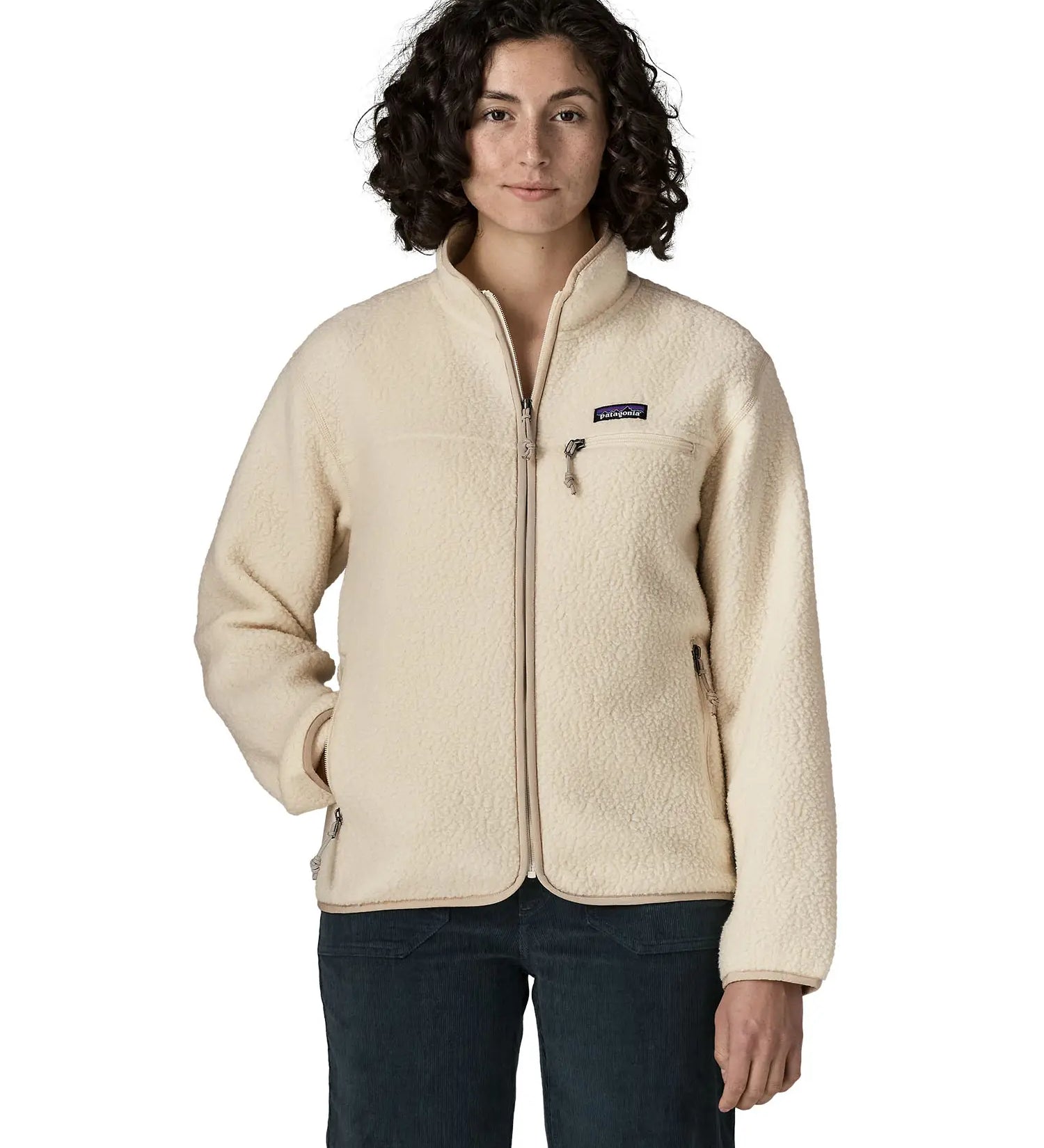 Woman wearing Patagonia's retro pile fleece jacket in natural cream. showing full front zip, chest and side pocket. fleece has a relaxed fit