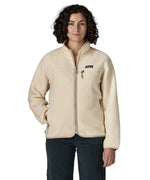 Woman wearing Patagonia's retro pile fleece jacket in natural cream. showing full front zip, chest and side pocket. fleece has a relaxed fit