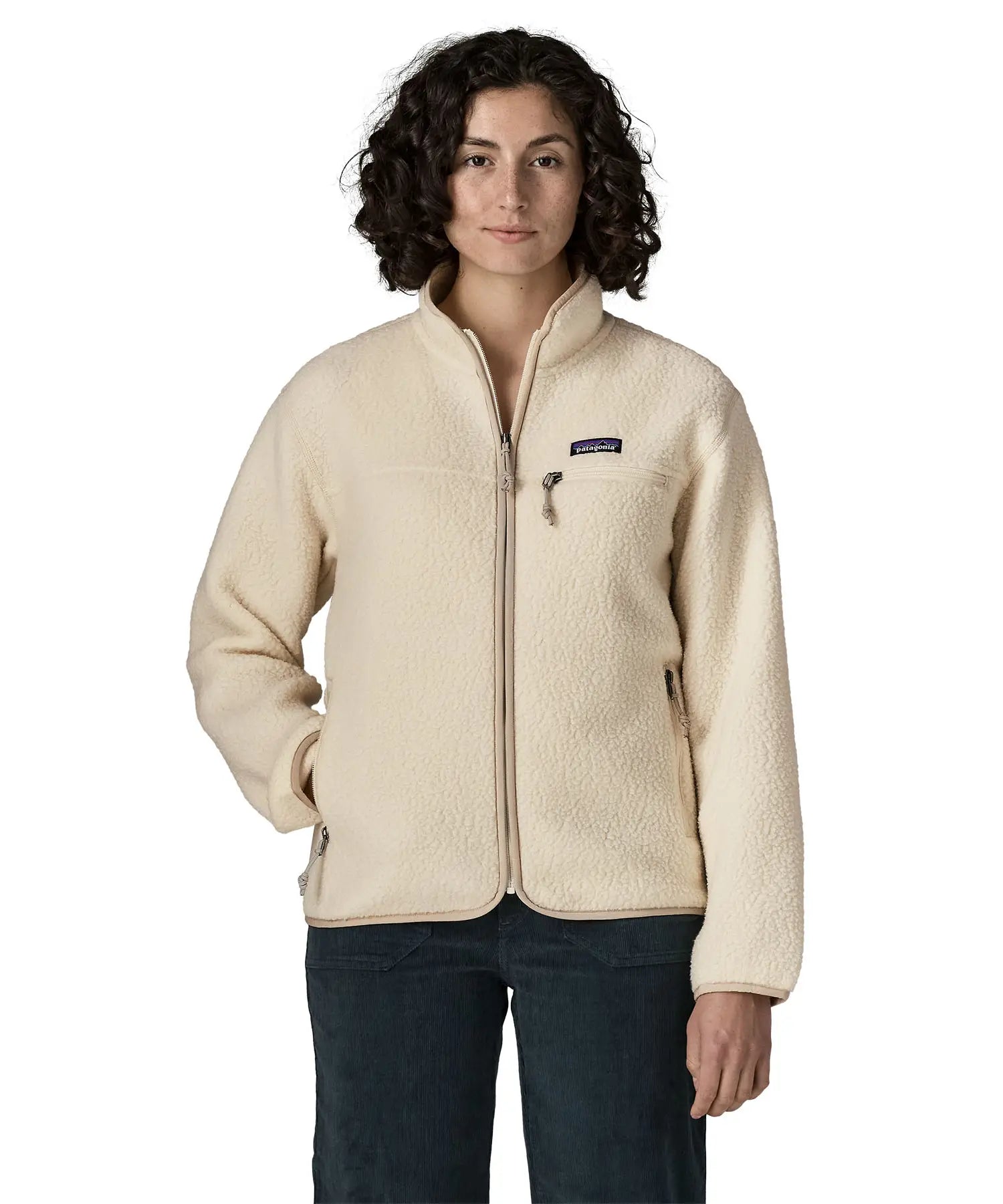 Woman wearing Patagonia's retro pile fleece jacket in natural cream. showing full front zip, chest and side pocket. fleece has a relaxed fit