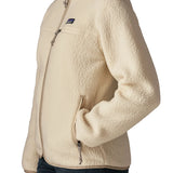 Side of woman wearing Patagonia's retro pile fleece jacket in natural cream. showing hand in the side pocket