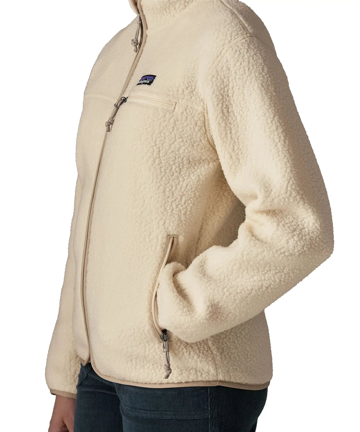Side of woman wearing Patagonia's retro pile fleece jacket in natural cream. showing hand in the side pocket