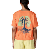 Woman wearing Patagonia's women's easy cut short sleeve t-shirt in bright orange with blue tree roots graphic on the back