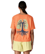 Woman wearing Patagonia's women's easy cut short sleeve t-shirt in bright orange with blue tree roots graphic on the back