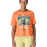 Woman wearing Patagonia's women's easy cut short sleeve t-shirt in bright orange with retro run like roots graphic on the front