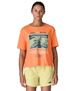 Woman wearing Patagonia's women's easy cut short sleeve t-shirt in bright orange with retro run like roots graphic on the front
