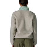 Back of the woman wearing Patagonia women's synchilla fleece jacket in light grey showing the light blue collar turned up