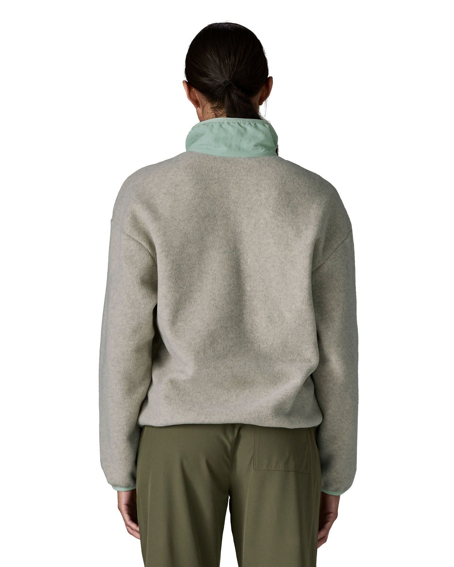 Back of the woman wearing Patagonia women's synchilla fleece jacket in light grey showing the light blue collar turned up