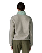 Back of the woman wearing Patagonia women's synchilla fleece jacket in light grey showing the light blue collar turned up