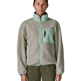 Woman wearing Patagonia's women's synchilla fleece jacket in light grey and blue trim. With the front zip fully fastened 