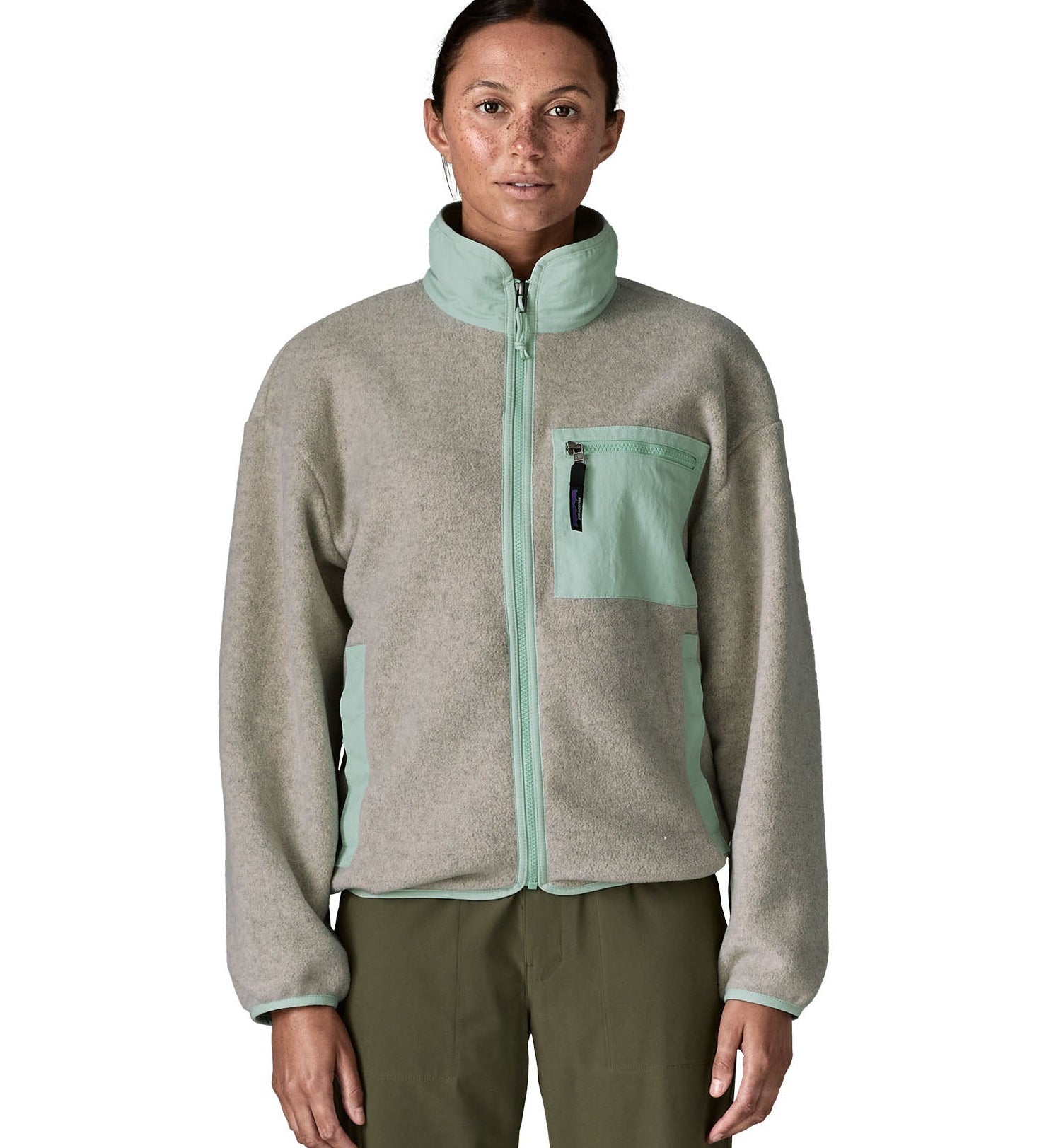 Woman wearing Patagonia's women's synchilla fleece jacket in light grey and blue trim. With the front zip fully fastened 