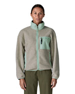 Woman wearing Patagonia's women's synchilla fleece jacket in light grey and blue trim. With the front zip fully fastened 