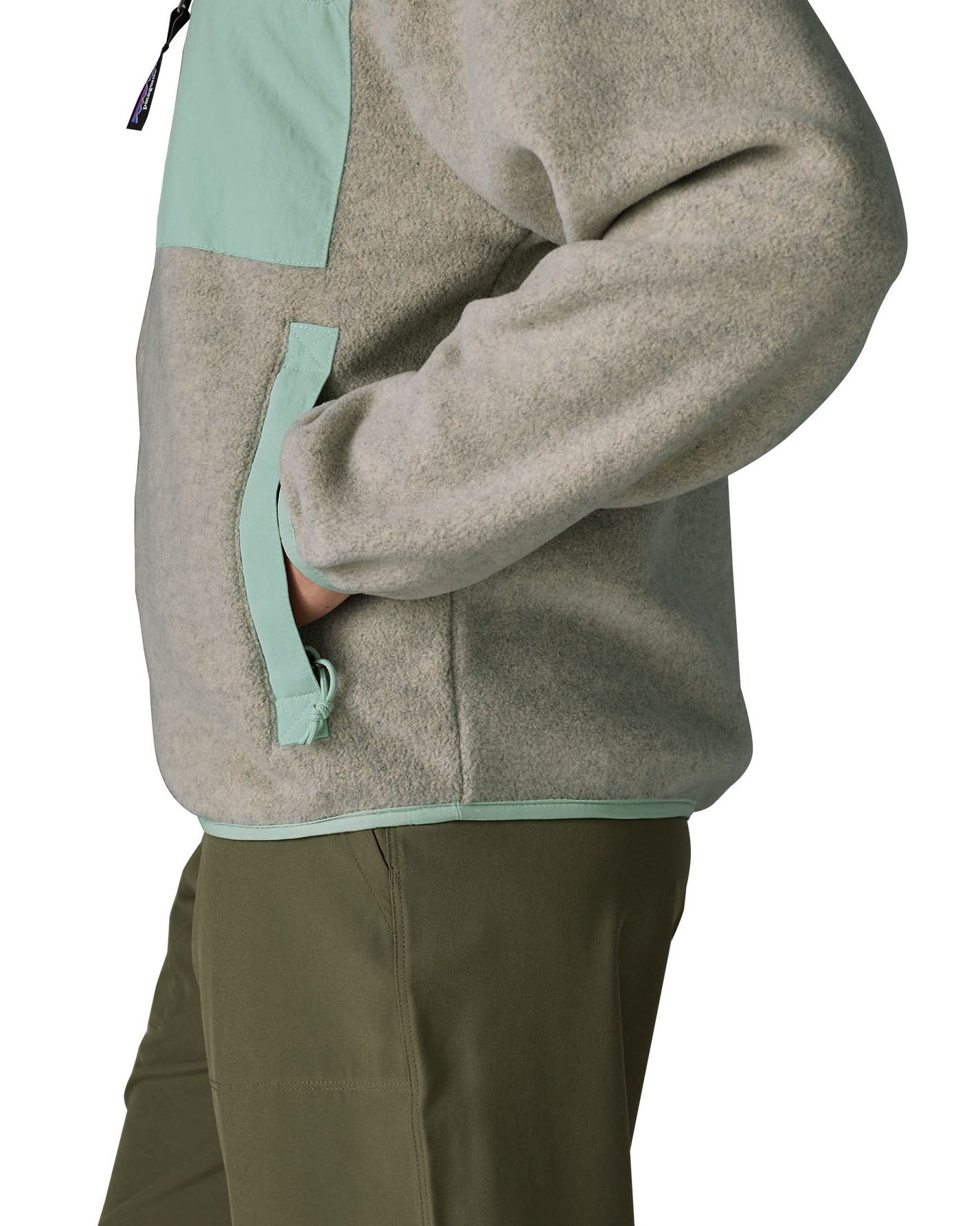 Side of a woman wearing Patagonia's women's synchilla fleece jacket in light grey. Jacket has relaxed fit and sits at the hips