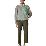 Woman wearing Patagonia women's synchilla fleece jacket in light grey and blue trim. Jacket has relaxed fit and sits at the hips