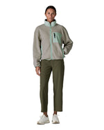 Woman wearing Patagonia women's synchilla fleece jacket in light grey and blue trim. Jacket has relaxed fit and sits at the hips