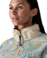 Close up of Woman wearing Patagonia's synchilla fleece with an abstract pastel retro design showing the cream turned up collar