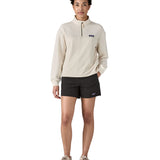 Woman wearing Patagonia quick drying women's baggies shorts in black with hand in side pocket. Shorts have loose fit