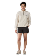 Woman wearing Patagonia quick drying women's baggies shorts in black with hand in side pocket. Shorts have loose fit