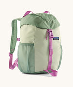 The Patagonia Kids Refugito 12L Backpack   in ellwood green , a pastel green backpack pink buckle and handle detail. Features 2 side mesh pockets in contrast green. A Logo patch is stitched on the front panel.
