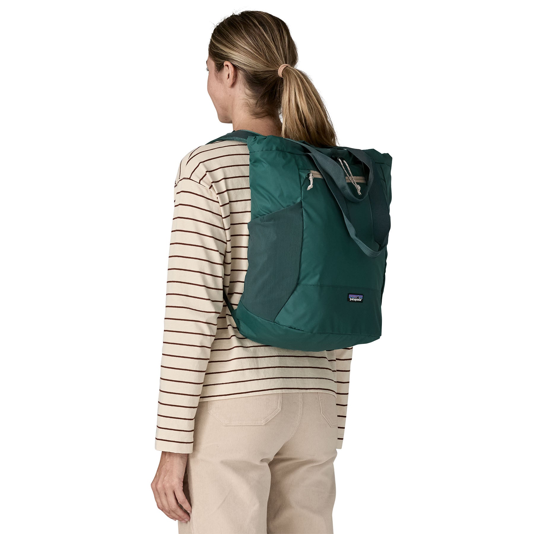 Patagonia Terravia tote bag in cascade green worn by a adult on the back available at Babipur showing the carrying handle details and side pockets for holding bottles