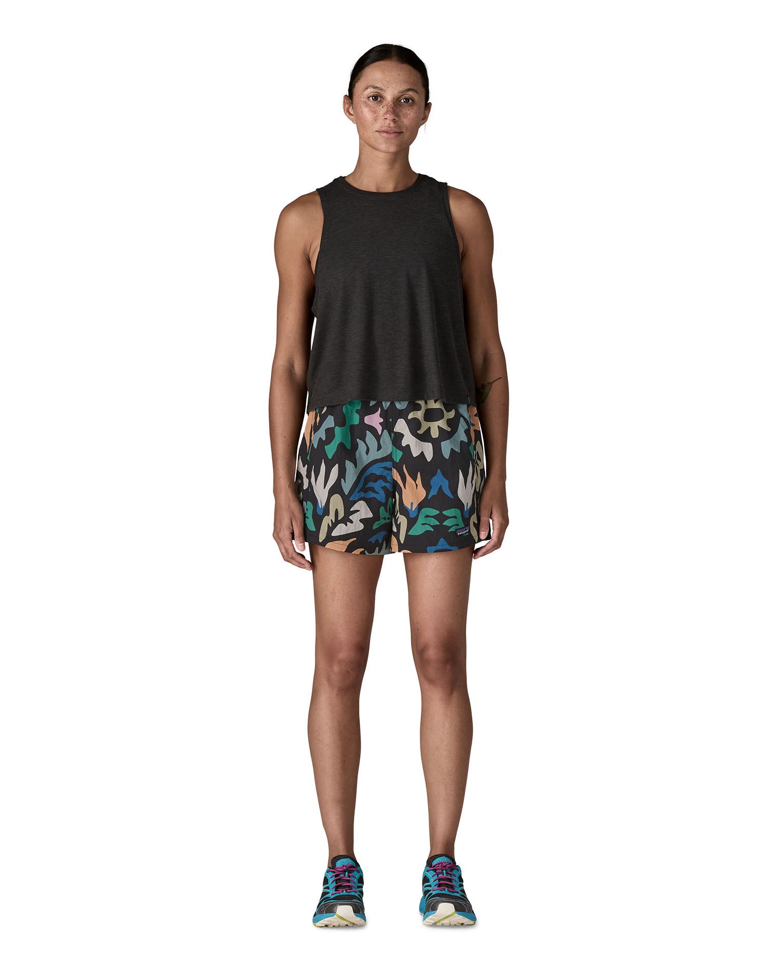 Woman wearing Patagonia quick drying women's baggies shorts in black with repeating abstract design. Shorts have loose fit