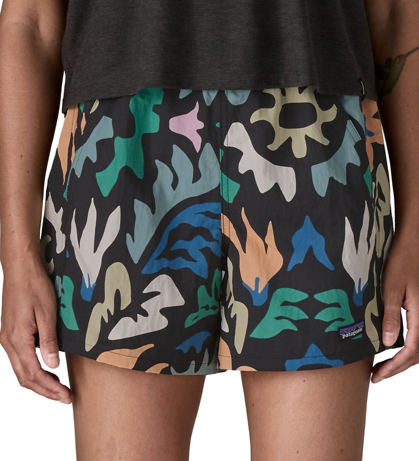 Woman wearing Patagonia quick drying women's baggies shorts in black with repeating abstract design. Shorts have a loose fit