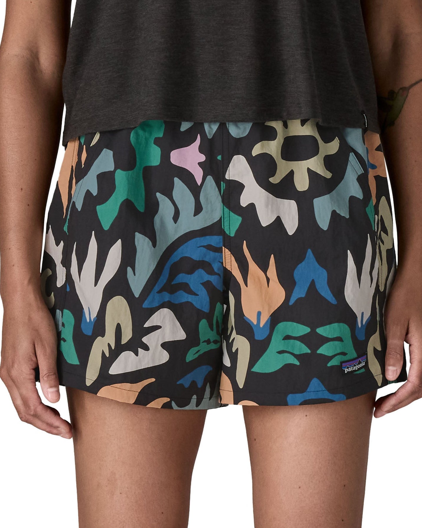 Woman wearing Patagonia quick drying women's baggies shorts in black with repeating abstract design. Shorts have a loose fit