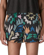 Woman wearing Patagonia quick drying women's baggies shorts in black with repeating abstract design. Shorts have a loose fit