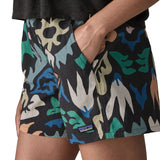Side of woman wearing Patagonia quick drying women's baggies shorts in black with repeating abstract design with hand in side pocket