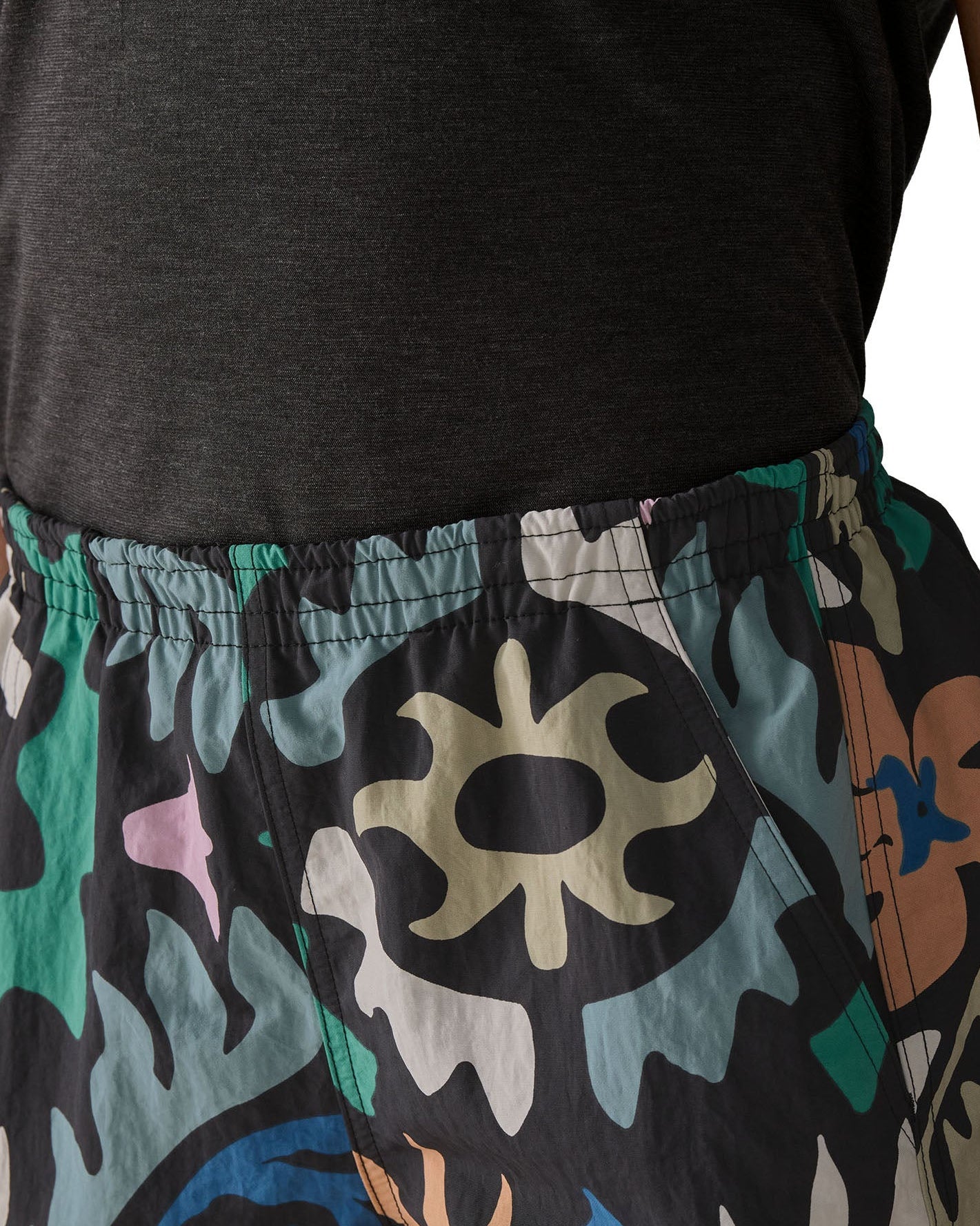 Woman wearing Patagonia quick drying women's baggies shorts in black with repeating abstract design shows elasticated waist band