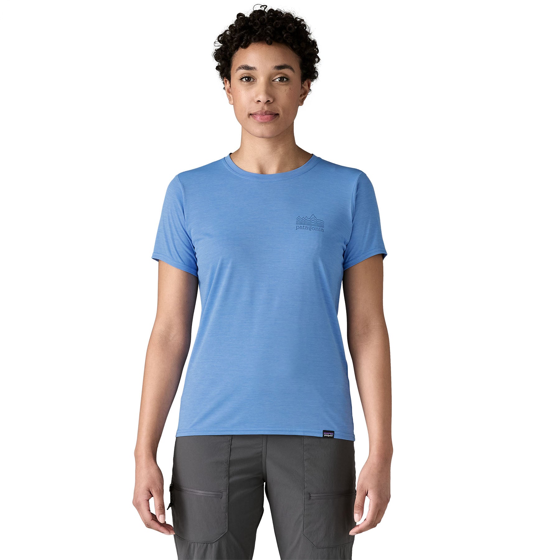 A woman wearing The Patagonia Women's Capilene Cool Daily Graphic Shirt in abundant blue, with a small logo on the left of the chest.
